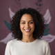 Close-up portrait of a smiling woman with diverse features, exuding happiness and relaxation against a soft, blurred backgrou